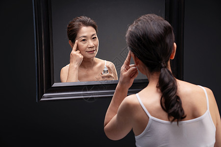 中年女人对着镜子涂抹爽肤水图片