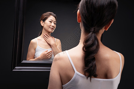 中老年女人对着镜子做颈部护理图片