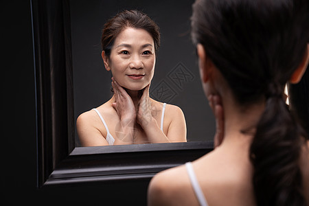 中老年女对着镜子做颈部护理图片
