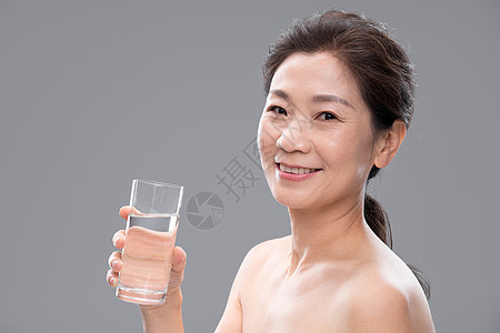 中年女人拿着玻璃杯喝水高清图片