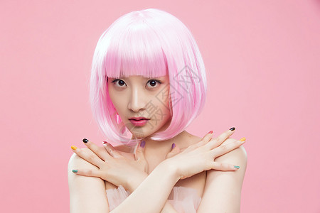 水平构图青年女人粉色背景带着假发涂着指甲油的个女孩图片