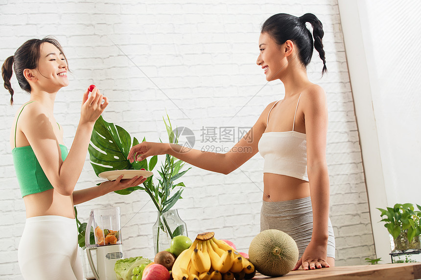 青年女人友谊站着年轻闺蜜在家吃水果图片