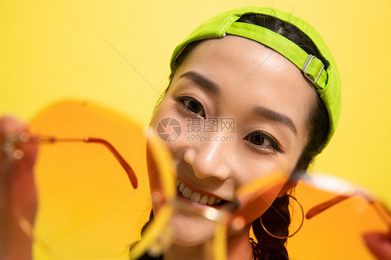 乐趣情绪黄色背景手扶墨镜的时尚年轻女孩图片
