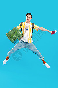 抱着行李箱跳跃的年轻男人图片