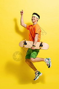 拿着滑板跳跃的活力青年男人图片
