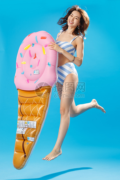 拿着冰淇淋形状的浮排跳跃的比基尼美女图片