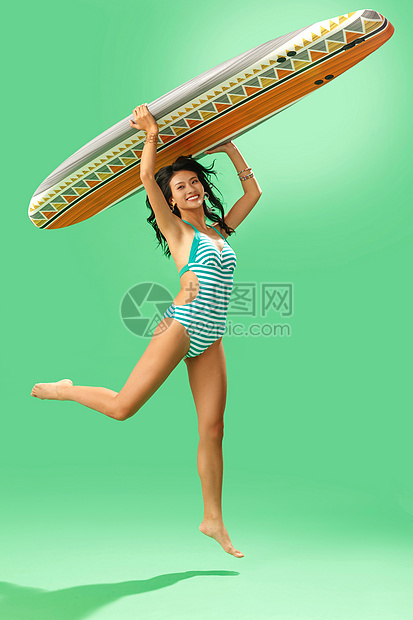 穿泳装的美女举着冲浪板跳跃图片