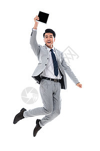 高举手臂白领兴奋拿着平板电脑跳跃的商务男士图片