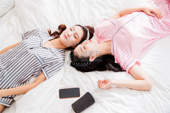 健康生活方式年轻闺蜜躺在床上敷面膜图片