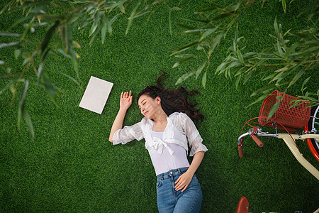 躺在草地上享受大自然的青年女人图片