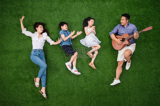 青年人侧卧青年女人幸福的一家四口在草地上唱歌图片