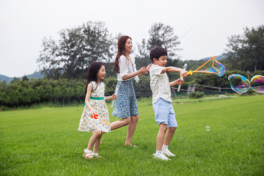 多色的母亲非都市风光妈妈带着两个孩子在草地上快乐玩耍