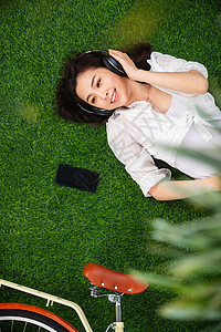 逃避现实休闲装人躺在草地上听音乐的青年女人图片
