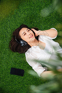 躺在草地上听音乐的青年女人图片