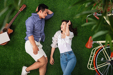 青年伴侣躺在草地上聊天图片