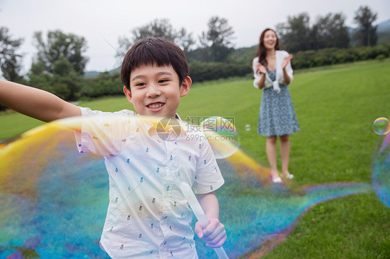 短袖树绿色快乐的母子在草地上玩耍吹泡泡图片