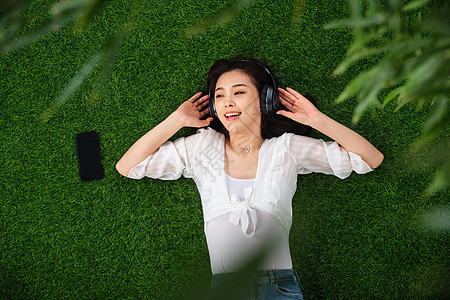 草坪公园宁静躺在草地上听音乐的青年女人图片