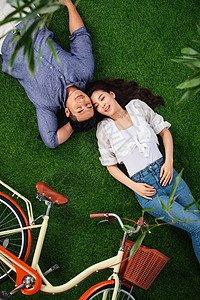 30岁到34岁爱相伴甜蜜的青年伴侣躺在草地上图片