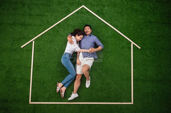 丈夫公园短裤青年伴侣躺在草地上的房子轮廓里图片