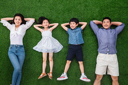 短裤连衣裙两个孩子的家庭幸福的一家四口躺在草地上图片