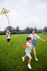 奔跑线男孩东亚选择对焦快乐的一家四口在草地上放风筝背景