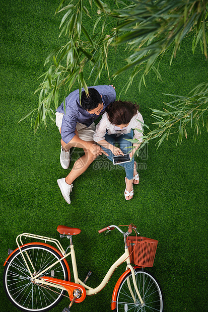 无忧无虑高视角爱青年伴侣坐在草地上使用平板电脑图片