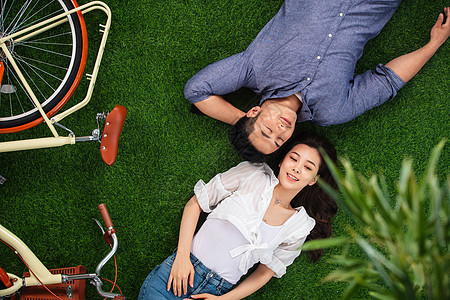 25岁到29岁快乐享乐甜蜜的青年伴侣躺在草地上图片
