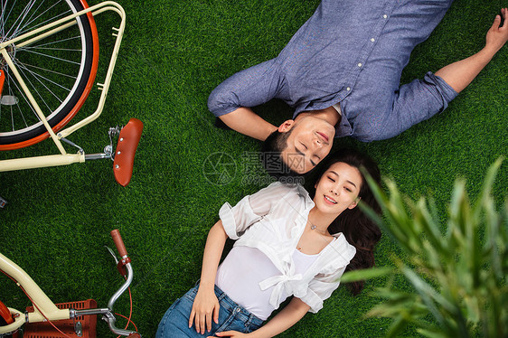 25岁到29岁快乐享乐甜蜜的青年伴侣躺在草地上图片