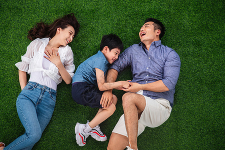 快乐的三口之家躺在草地上嬉戏图片
