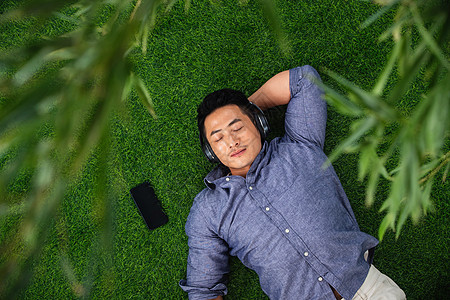 草坪植物人青年男人躺在草地上听音乐图片