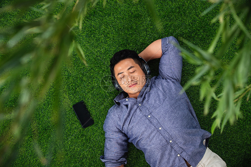 草坪植物人青年男人躺在草地上听音乐图片