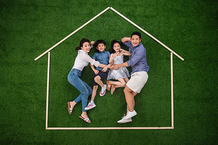 假日兄弟姐妹东亚幸福的四口之家躺在草地上的房子轮廓里图片