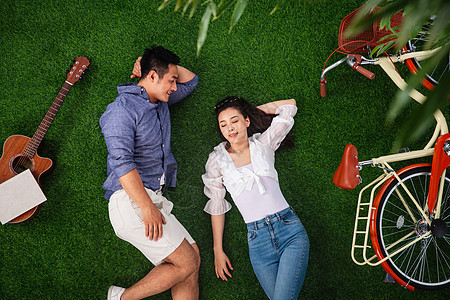 绿色睡觉侧卧幸福的青年伴侣躺在草地上享受休闲时光图片