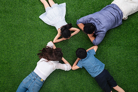 幸福的一家四口面对面趴在草地上图片