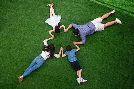 幸福的一家四口手牵着手趴在草地上图片