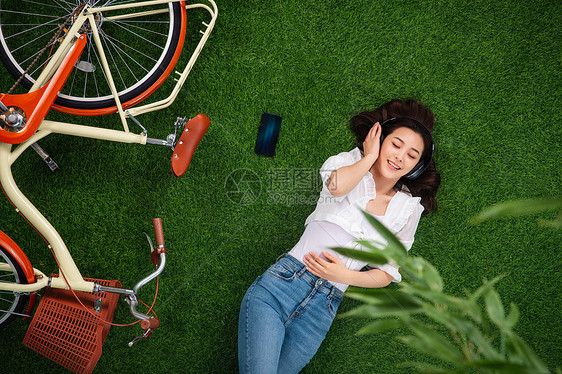 竹子叶子亚洲人躺在草地上听音乐的年轻女人图片