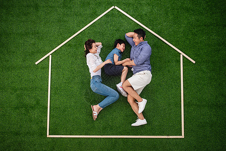 温馨活力休闲装快乐的一家三口躺在草地上的房子轮廓里图片