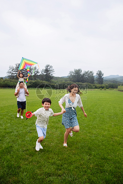 亚洲放松儿子快乐的一家四口在草地上放风筝图片