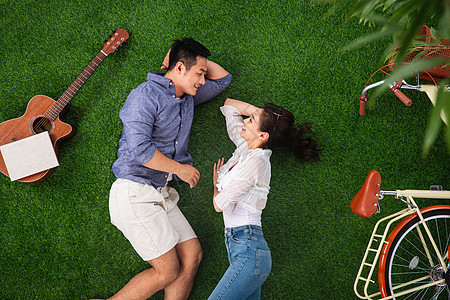 青年伴侣躺在草地上享受休闲时光图片