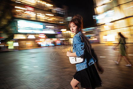 包商业区街道夜晚行走的路上的青年女人图片