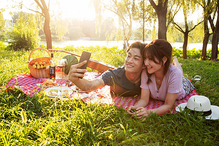 女人浪漫裙子趴在草地上拍照的幸福情侣图片