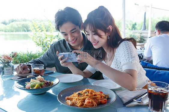 用手机拍美食的快乐情侣图片