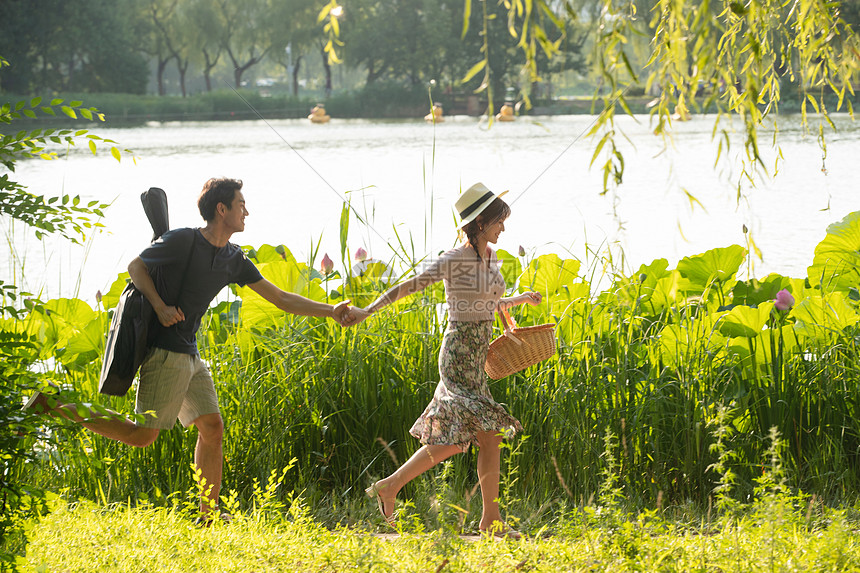 湖欢乐风景手牵手郊游的幸福情侣