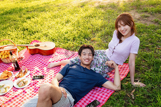 青年人注视镜头吉他躺在草地上的幸福情侣图片