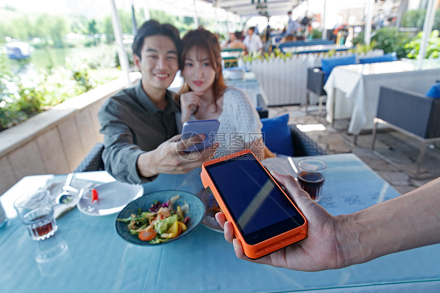 消费休闲青年夫妇年轻情侣在餐厅用手机付款图片