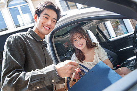 青年人周末活动愉悦青年情侣拿着购物袋站在汽车旁图片