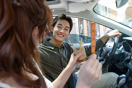 坐在汽车里的青年情侣吃东西图片