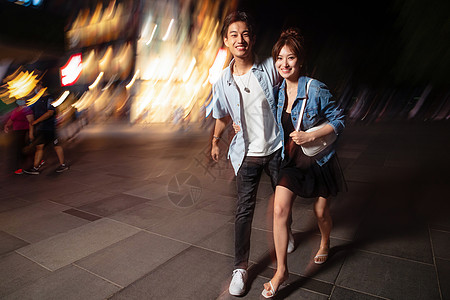 夜晚的城市道路运动模糊商店建筑夜晚逛街的快乐情侣背景