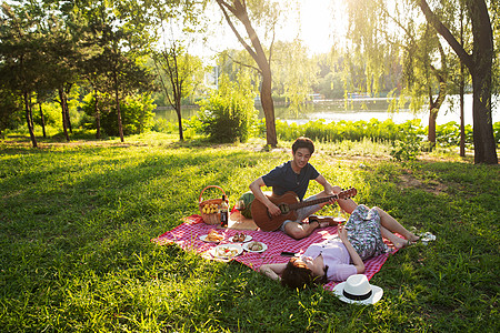 东方人非都市风光日光在公园里弹吉他的幸福情侣图片