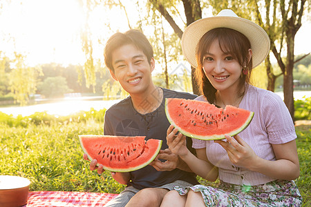 男人吃西瓜青年情侣坐在公园里吃西瓜背景